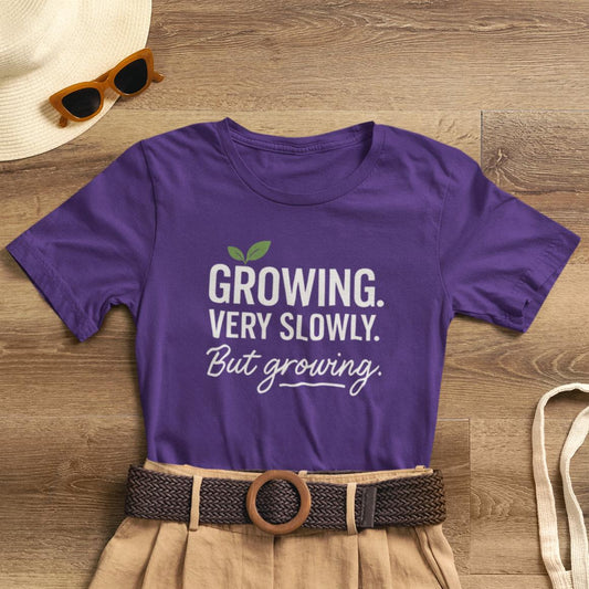 Light-colored Growing Very Slowly But Growing T-Shirt by Printify featuring gentle growth and emotional healing design on soft fabric.
