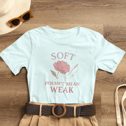 Feminist floral empowerment T-shirt by Printify featuring the "Soft Doesn’t Mean Weak" slogan on a soft, comfortable tee