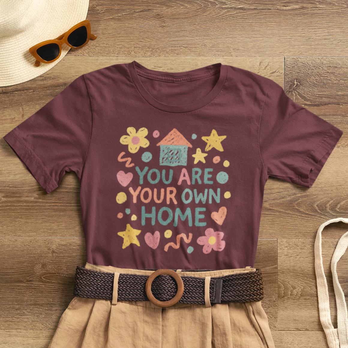 Pastel doodle quote tee featuring "You Are Your Own Home" design by Printify, showcasing naive art aesthetic.