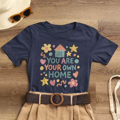 Pastel doodle t-shirt featuring 'You Are Your Own Home' quote, soft fabric, and naive art aesthetic by Printify.