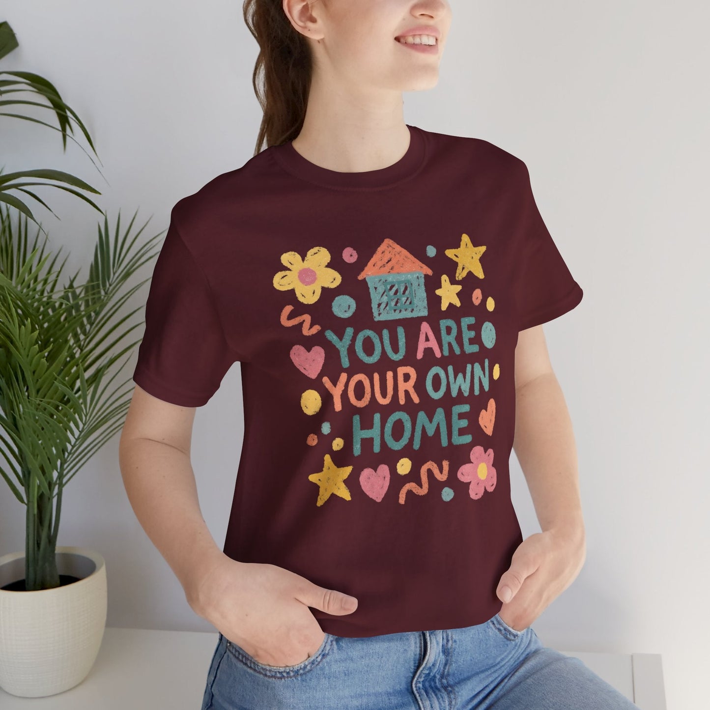 Pastel doodle t-shirt featuring the quote "You Are Your Own Home" in a naive art aesthetic by Printify.