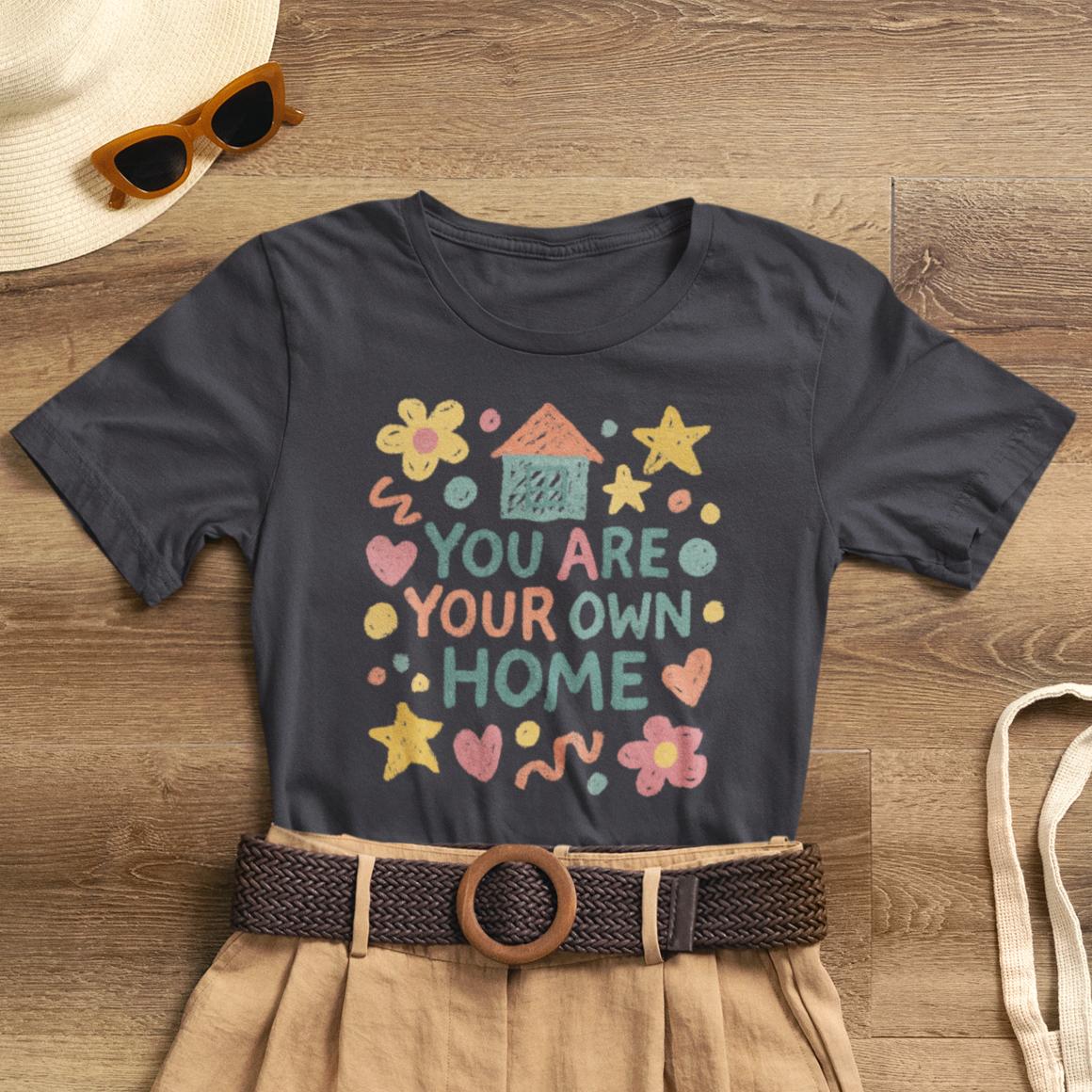Pastel doodle t-shirt with "You Are Your Own Home" quote, featuring naive art aesthetic by Printify.