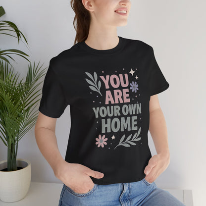 White Printify T-Shirt with "You Are Your Own Home" slogan, casual fit, soft fabric, ideal for self-love and healing reminders.